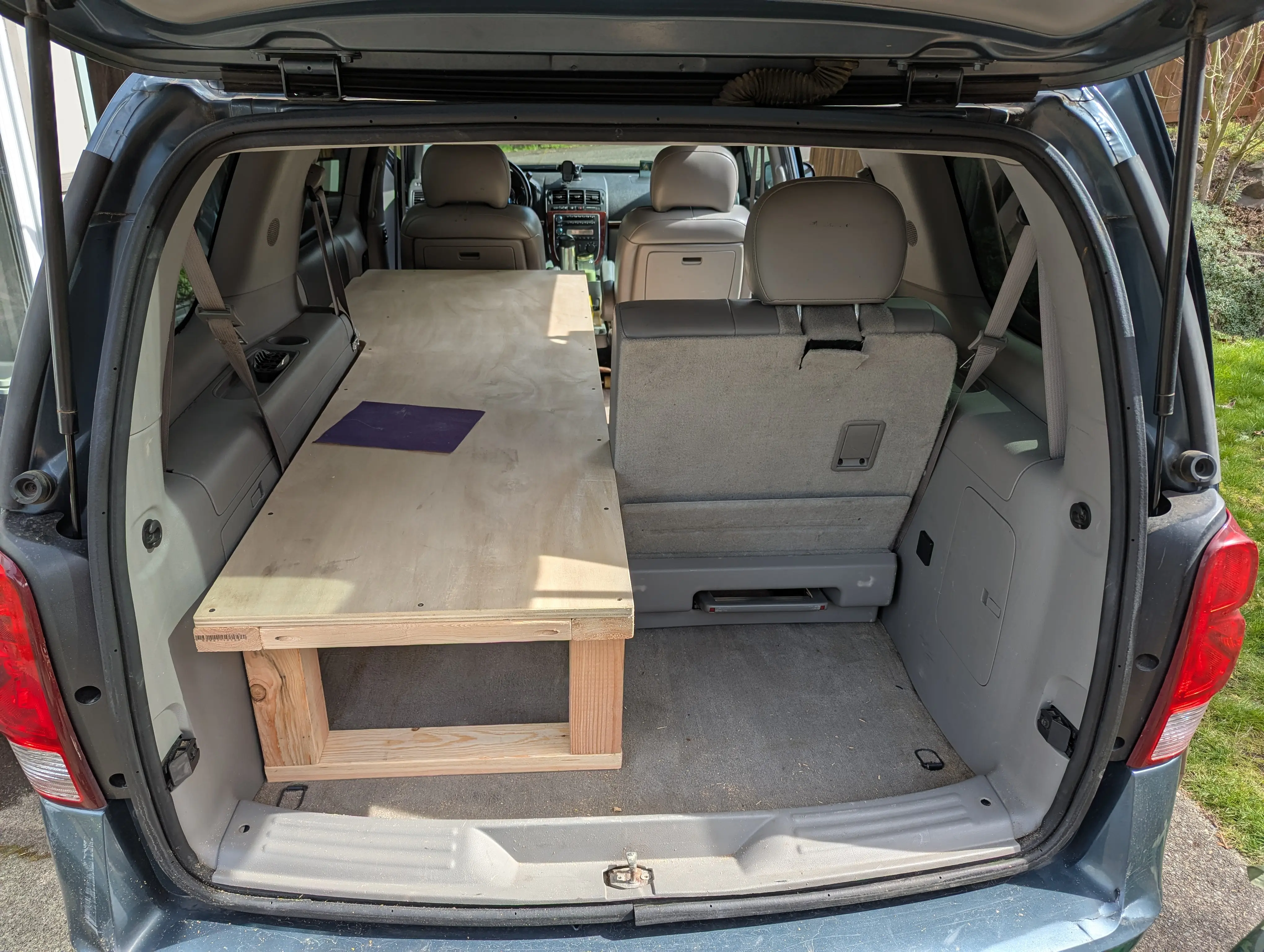 The wooden bed platform pictured installed next to a rear seat from the vehicle